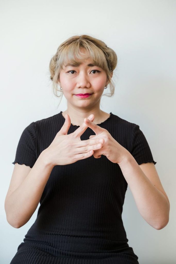 Kobieta w czarnym stroju prezentuje język migowy
